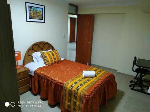 um quarto com uma cama com um cobertor laranja em INTI SUMAQ WASI em Cusco
