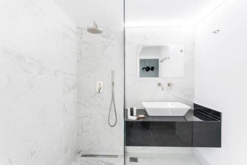 a white bathroom with a sink and a shower at Dion Suites in Athens