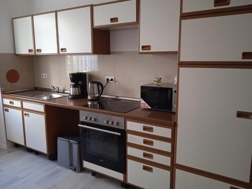 a kitchen with a stove and a sink and a refrigerator at Gästewohnung OC in Oschersleben