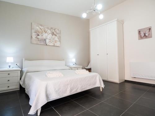 a bedroom with a white bed and a white cabinet at SweetHome - MORADA in Torpè