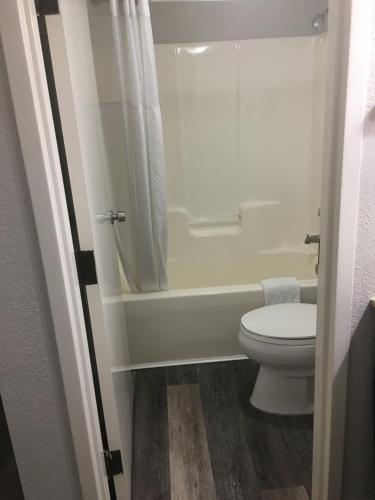 a bathroom with a white toilet and a tub and a toilet at Days Inn by Wyndham Port Charlotte Town Center in Port Charlotte