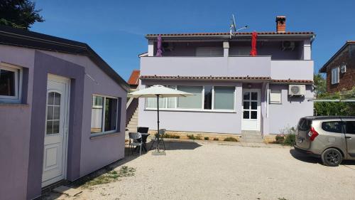 a house with an umbrella and a car parked in the driveway at Apartman Lavanda in Peroj
