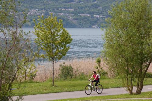 a man riding a bike down a path next to a lake at Hôtel du Poète in Aix-les-Bains