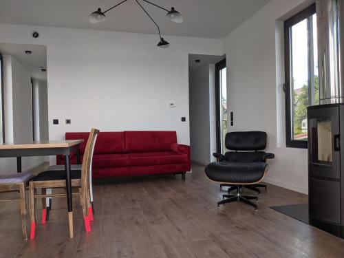 a living room with a red couch and a table and chairs at Dom na Wodzie in Kruklanki