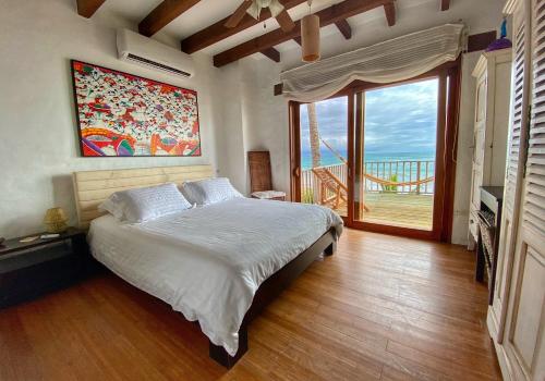 a bedroom with a large bed and a large window at Casa Baronesa Waterfront Villa in Puerto Villamil