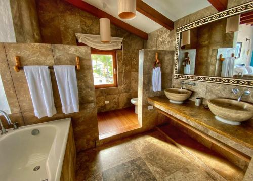 y baño con bañera, lavabo y espejo. en Casa Baronesa Waterfront Villa, en Puerto Villamil