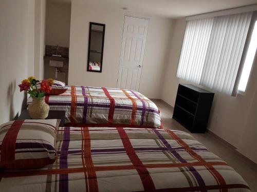 ein Schlafzimmer mit 2 Betten und einer Vase aus Blumen in der Unterkunft Thiers Appt in Mexiko-Stadt