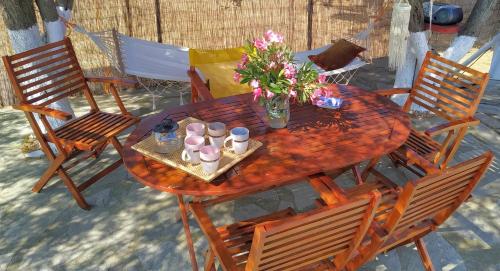 una mesa de madera con sillas y un jarrón de flores. en Vanna's Holiday House, en Ierissos