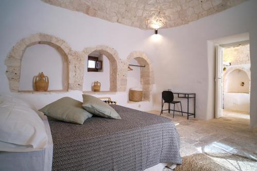 a white bedroom with a bed and a table at Borgo SantaMarta in Noci