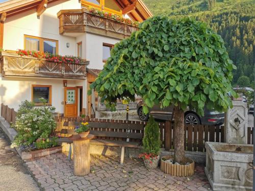ein Haus mit einer Bank und einem Baum davor in der Unterkunft Alpenhaus Bichlbach in Bichlbach