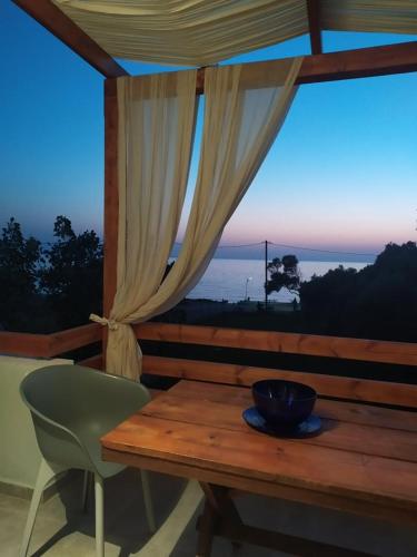 a wooden table and chair on a porch with a window at Lavender and Sea in Nea Potidaea