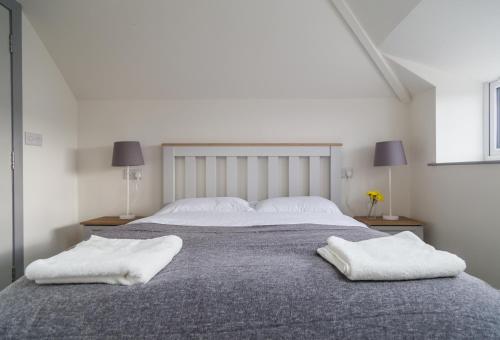 a bedroom with a large bed with two white towels on it at White Hall Portrush in Portrush