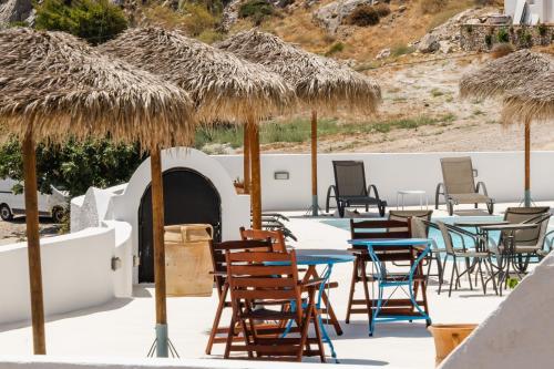 a group of tables and chairs with straw umbrellas at Ancient Thera Apartments in Kamari