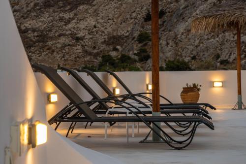 a group of chairs sitting next to a wall at Ancient Thera Apartments in Kamari