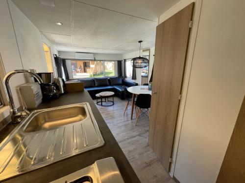a kitchen with a sink and a living room at Vakantiepark Klein Vink - A10 in Arcen