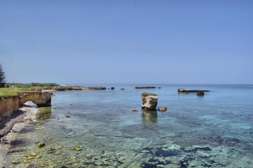 a body of water with a rock in the water at Masseria Bosco Mazza in Melendugno