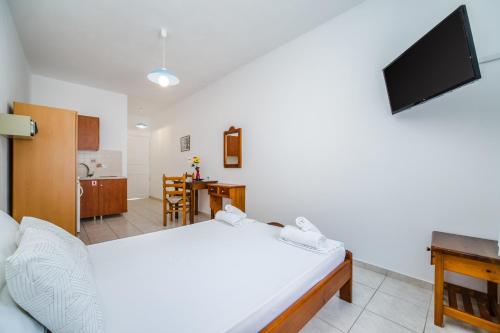 a bedroom with a white bed and a kitchen at Ancient Thera Apartments in Kamari