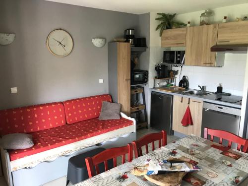 un salon avec un canapé rouge dans une cuisine dans l'établissement Village vacances Ardèche Odalys climatisé, à Salavas