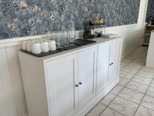 a white kitchen with a counter with mugs on it at Hotell Luspen in Storuman