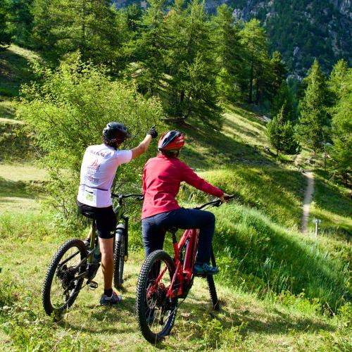 two people riding bikes on a grassy hill at Rifugio Baita Gimont in Cesana Torinese