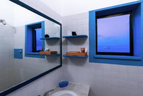 ein Bad mit einem Spiegel, einem Waschbecken und einem Fenster in der Unterkunft Casa di Sale - Chianalea in Scilla