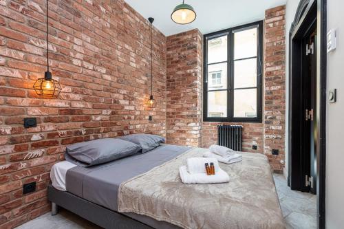 - une chambre aux murs de briques avec un lit et des serviettes dans l'établissement FEEL HOME - BUNICO, à Nice