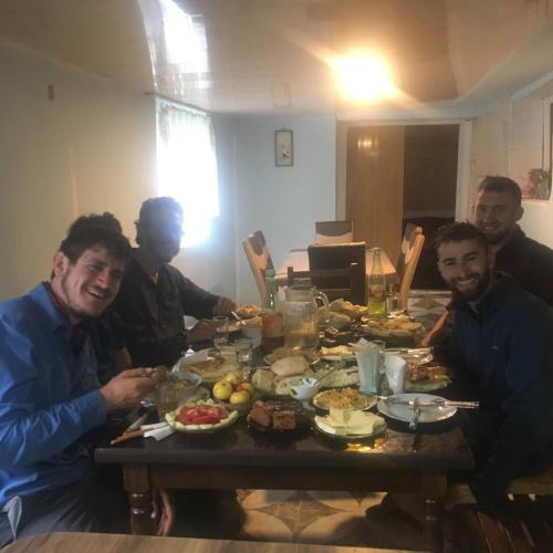 a group of men sitting around a table eating food at Sweet home in Lalkhori