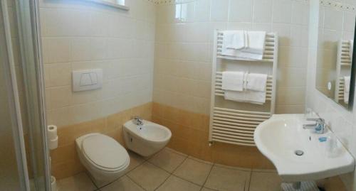 a white bathroom with a toilet and a sink at Hotel Miramare in Giulianova