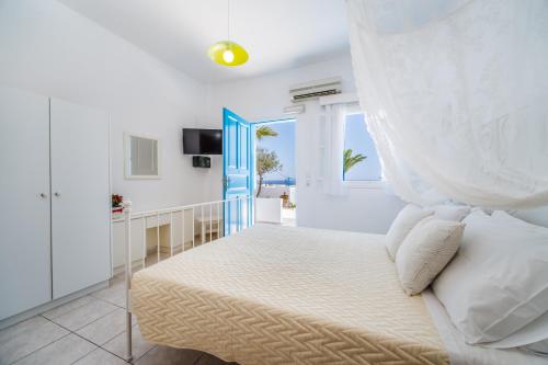 a bedroom with a bed with a curtain over it at Ancient Thera Apartments in Kamari