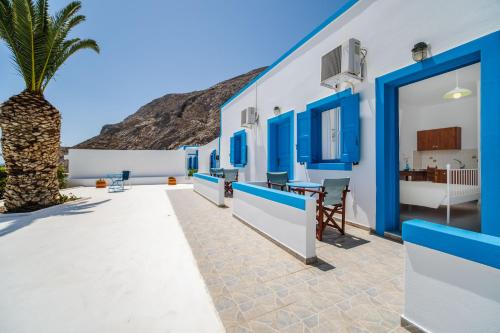 a house with blue windows and a palm tree at Ancient Thera Apartments in Kamari