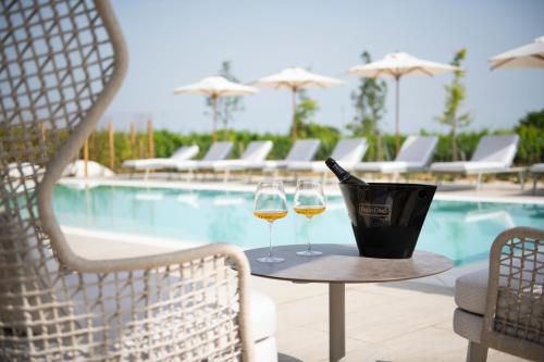 two glasses of wine on a table next to a pool at Magari Estates Boutique Hotel in Colognola ai Colli