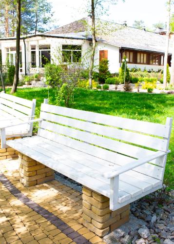 two white benches sitting on a brick patio at Zajazd Gołębiowski in Lipsko
