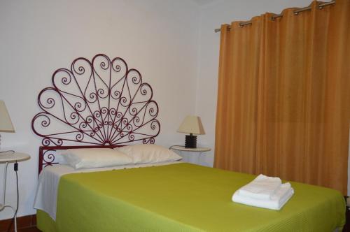een slaapkamer met een groen bed met 2 handdoeken erop bij CASA DA AVÓ in Vila Nova de Cacela