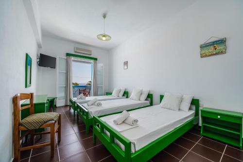 a room with three beds and a table and chairs at Ancient Thera Apartments in Kamari