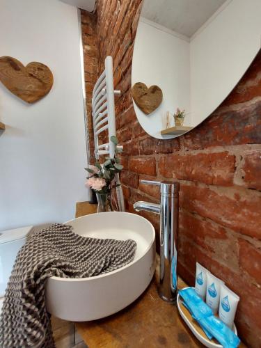 a bathroom with a sink and a brick wall at Siedlisko Farmhouse in Okszów