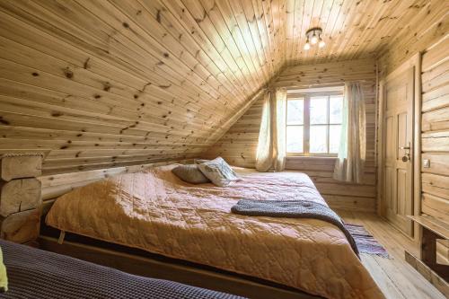 a bedroom with a bed in a log cabin at Baltās anemones in Jumprava