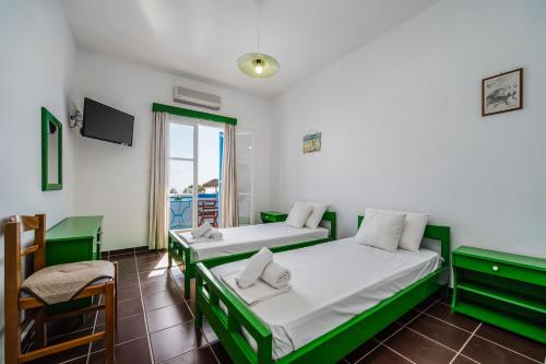 a room with two beds and a table and a chair at Ancient Thera Apartments in Kamari