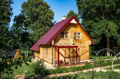 a small wooden house with a red roof at Baltās anemones in Jumprava