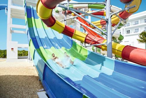 a couple riding on a water slide at a water park at Riu Republica - Adults Only - All Inclusive in Punta Cana