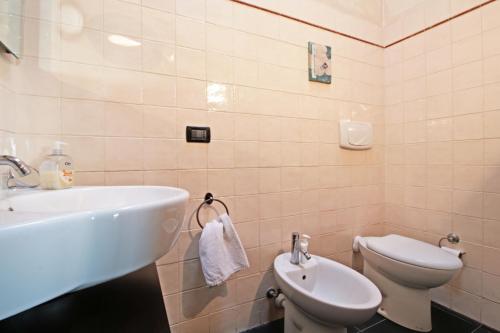 a white bathroom with a sink and a toilet at Albachiara home - vista mare in Cipressa