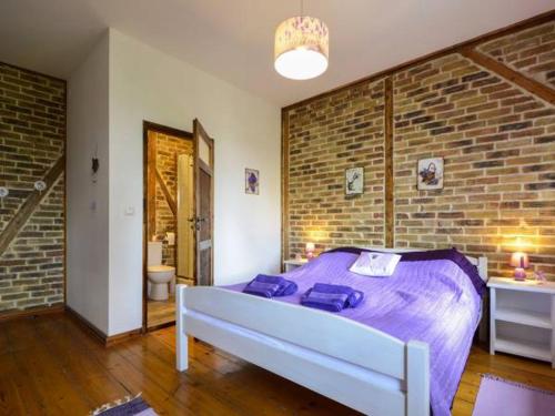 a bedroom with a bed with purple sheets and a brick wall at Willa Sielsko Anielsko in Szklarska Poręba