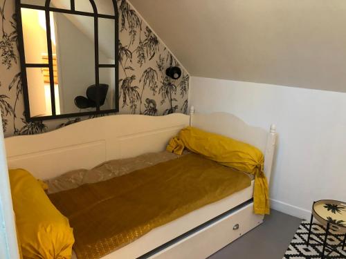 Cette chambre comprend un lit avec des draps jaunes et un miroir. dans l'établissement la Discrète, à Berck-sur-Mer