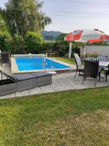 a swimming pool with a table and an umbrella at Reitbergs Nest in Eugendorf