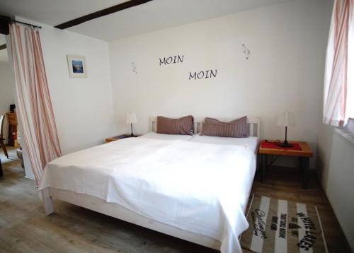 a bedroom with a white bed and a sign on the wall at Fischerhus In Krummin - nur für Urlauber in Krummin