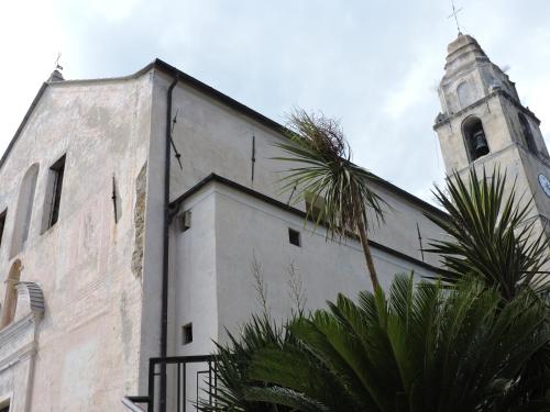 a church with a clock tower and a palm tree at Albachiara home - vista mare in Cipressa