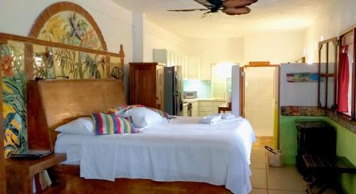 a bedroom with a white bed and a refrigerator at Mayan Beach Garden in El Placer