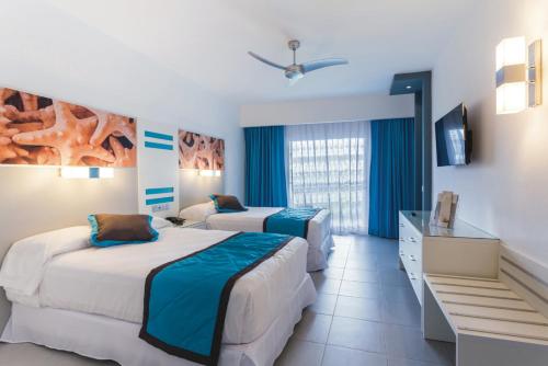 a hotel room with two beds and a television at Riu Republica - Adults Only - All Inclusive in Punta Cana