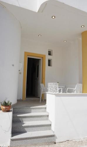 a hallway with white walls and stairs with chairs at Seafront Apartment Kalamaki in Kalamaki Heraklion