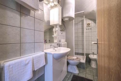 a white bathroom with a sink and a toilet at Kuća za odmor Tonka in Grižane