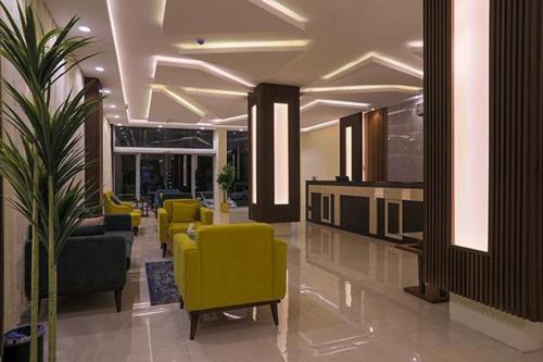 eine Lobby mit gelben Stühlen und Tischen in einem Gebäude in der Unterkunft فرس ابها للاجنحة الفندقية in Abha